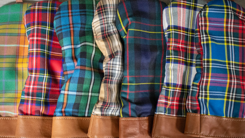 Collection of plaid driver covers with brown leather accents arranged in a row.